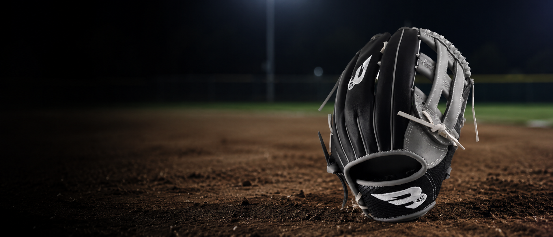 Baseball glove on a dirt field at night
